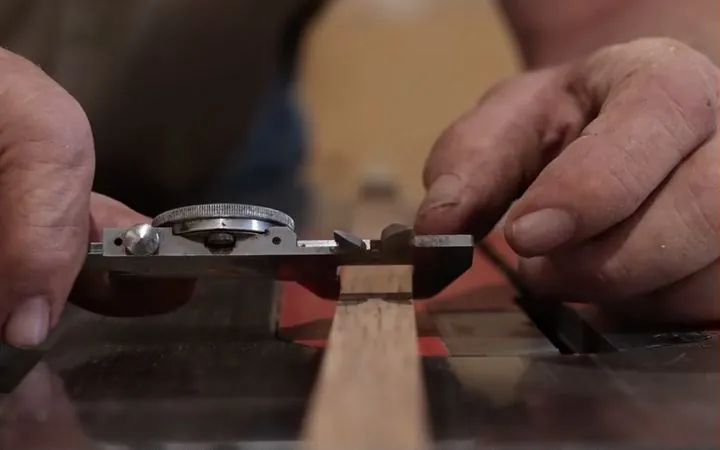 Hands setting a measuring gauge against a strip of wood