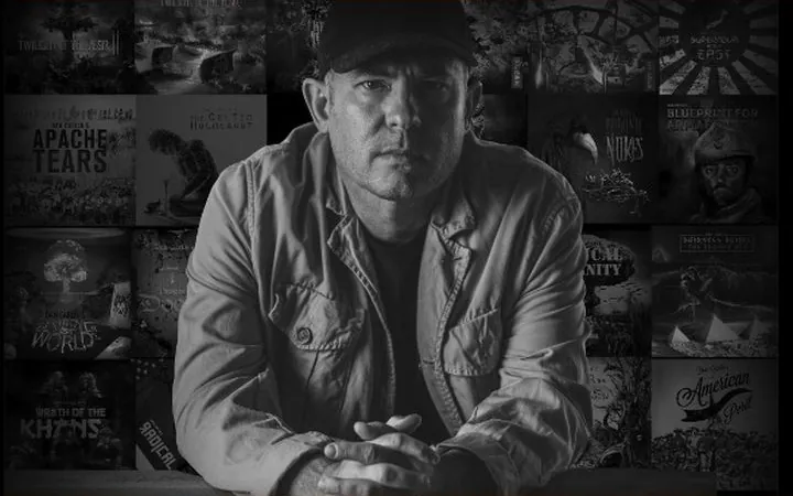 Dan Carlin in front of a wall of episode artwork