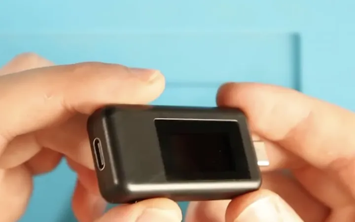 Hands holding a small USB power meter