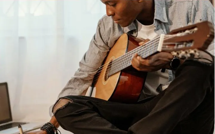 A guitarist writing notes while practicing