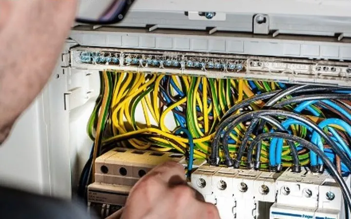 An electrician working on a breaker panel