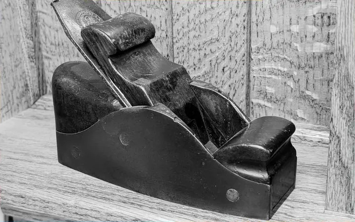 An antique wooden hand plane on a shelf