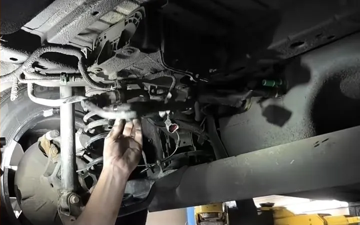 A mechanic’s hand working under a car on a lift