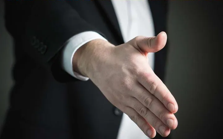 A man in a suit reaching out for a handshake