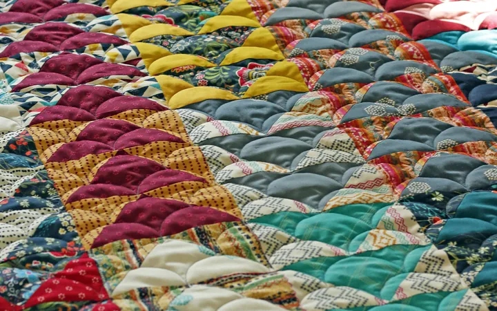 Close-up of a colorful quilt with curved, scalloped piecing